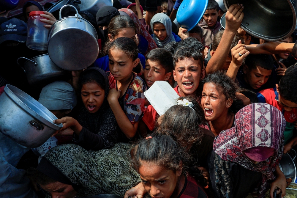 Palestinians wait to receive food from a charity kitchen, in Khan Younis, southern Gaza Strip, August 21, 2025. — Reuters pic