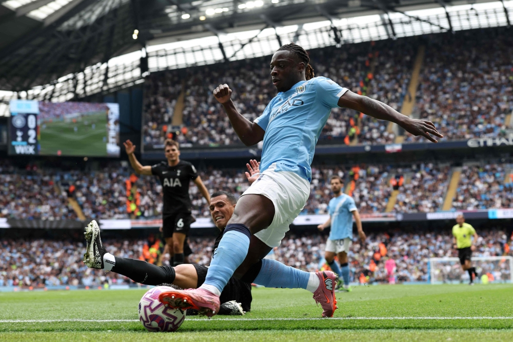 Tottenham Hotspur's Spanish defender #23 Pedro Porro slides in to tackle Manchester City's Belgian midfielder #11 Jeremy Doku during the English Premier League football match between Manchester City and Tottenham Hotspur at the Etihad Stadium in Manchester, north west England, on August 23, 2025. — AFP pic