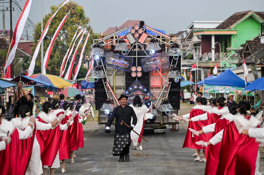 Dancers performing as they follow a truck mounted with a tower of subwoofers and spotlights. — AFP pic