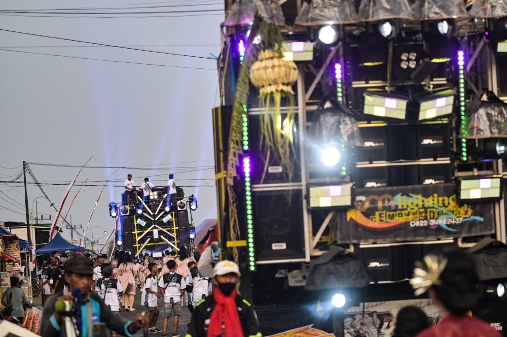 Crew members sitting atop a truck mounted with a tower of subwoofers during a ‘sound horeg’. — AFP pic