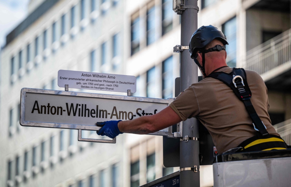 A worker installs a street sign bearing what is supposed to become the new name for the ‘Mohrenstrasse’ (Moor street), the ‘Anton-Wilhelm-Amo-strasse’ in Berlin’s Mitte district Aug 22, 2025. — AFP pic