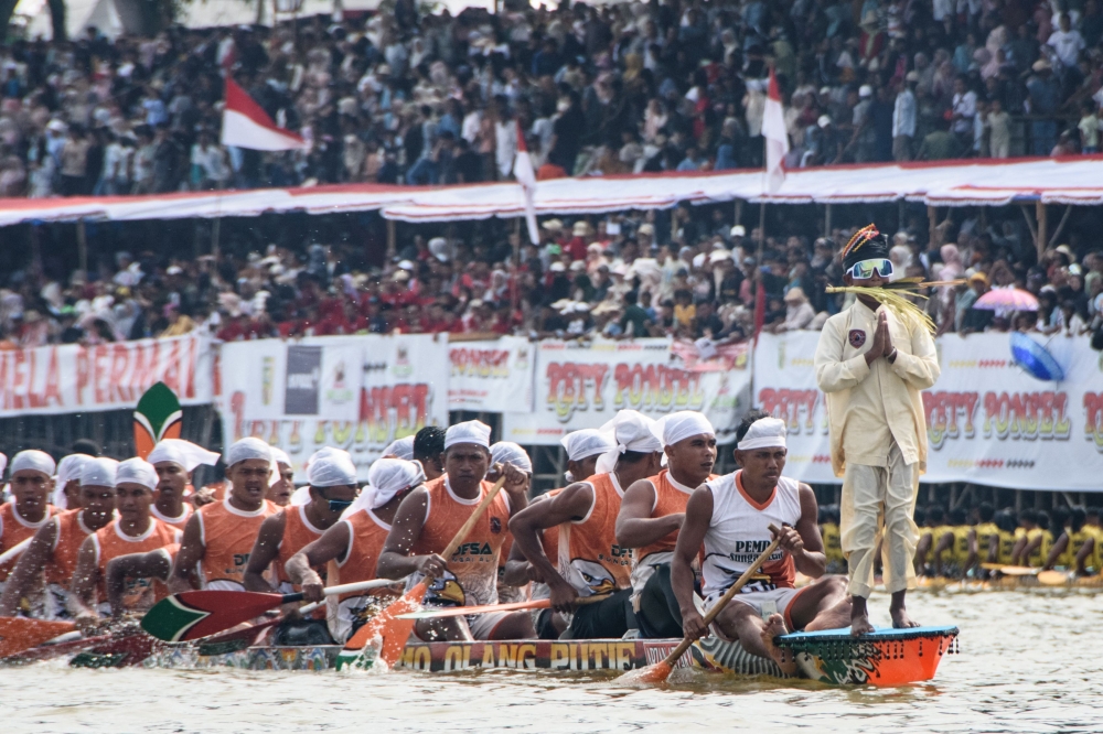 A boy dancer gestures while standing on the bow of his boat after the race during the Pacu Jalur longboat race festival on the Kuantan River in Kuantan Singingi Regency, Riau Province, on August 23, 2025. — AFP pic