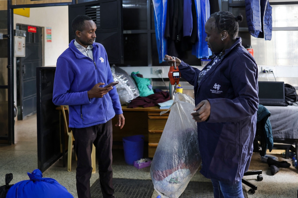 A resident uses digital credit earned from delivering plastic waste to a Human Needs Project (HNP) collection point to pay for laundromat services in the Kibera informal settlement of Nairobi, on August 11, 2025. — AFP pic