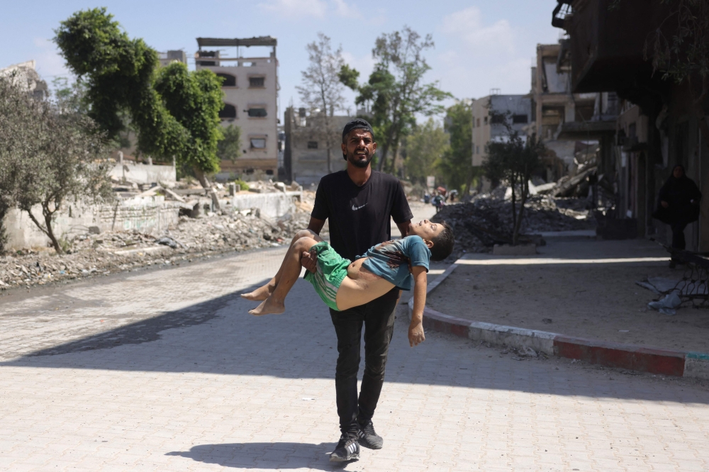 A man carries the body of a Palestinian boy, who was killed as he fled his home, in Jabalia’s Saftawy neighbourhood August 26, 2025. — AFP pic