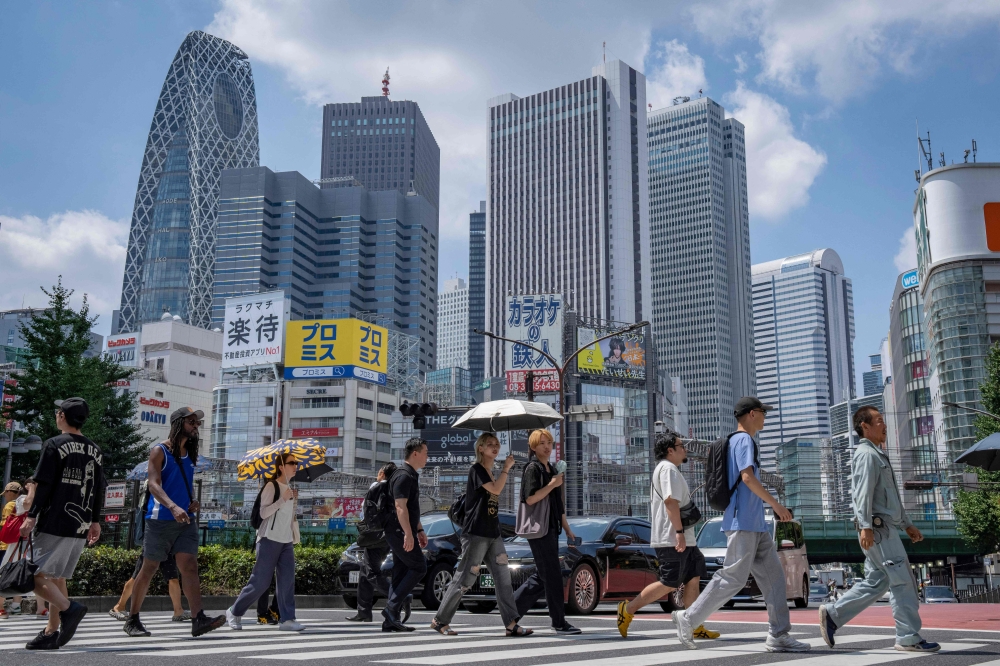 People cross a street at Shinjuku area in Tokyo August 25, 2025. — AFP pic