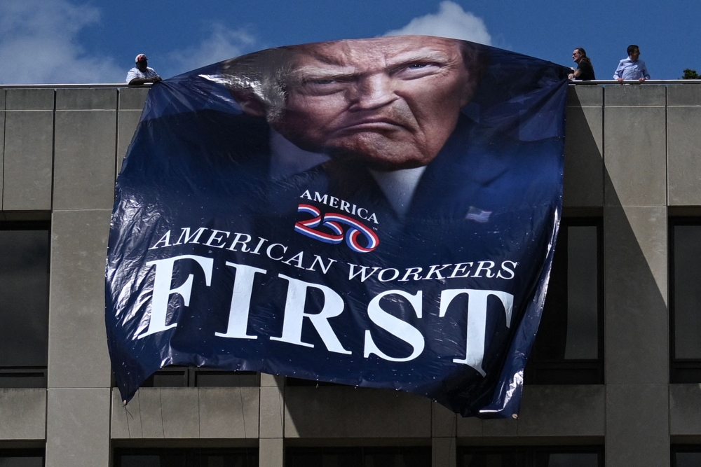 Workers hang a large photo of US President Donald Trump on the Department of Labor headquarters, Washington, DC August 27, 2025. — AFP