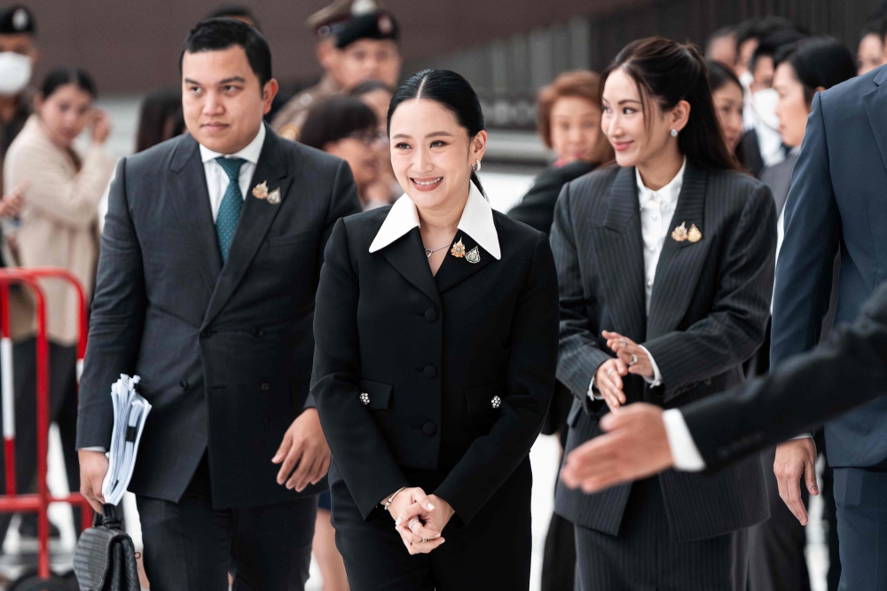 Thailand’s suspended Prime Minister Paetongtarn Shinawatra (centre) and her sister Pintongta Shinawatra (left) walk out of the Constitutional Court in Bangkok on August 21, 2025. — AFP pic