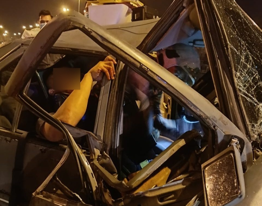 The accident at the airport flyover in Miri left the victim trapped in his crushed car.  — Picture courtesy of Fire and Rescue Department