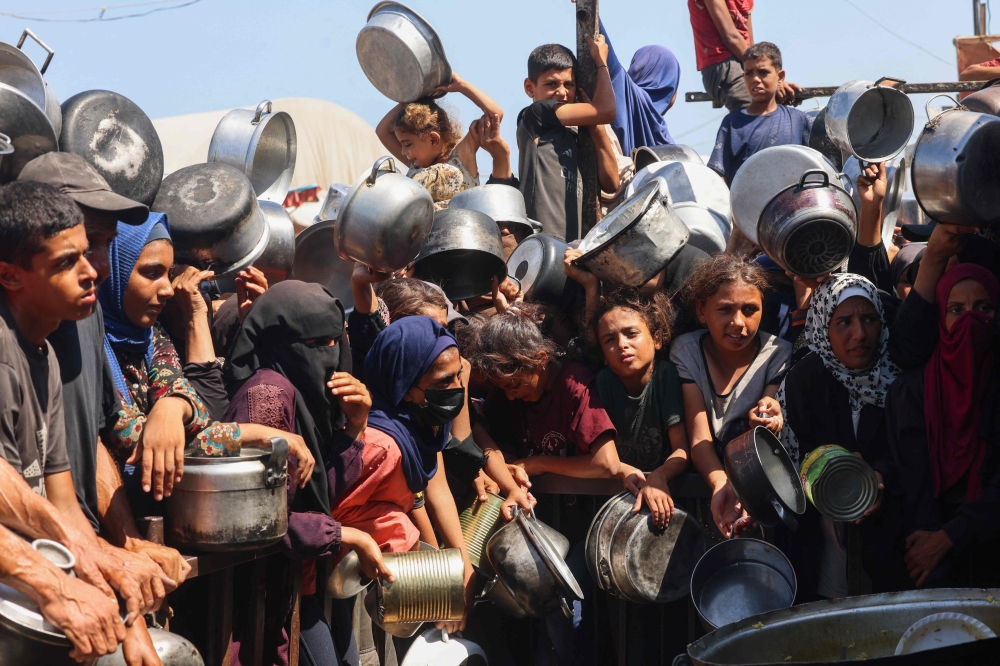 Palestinian women and children wait to receive food portions from a charity kitchen in Khan Yunis in the southern Gaza Strip on August 27, 2025. Pro-Palestinian activists preparing to set sail from Spain on Sunday for Gaza in dozens of boats carrying aid have called on governments to pressure Israel to allow their flotilla — the largest to date — through the naval blockade. — AFP pic