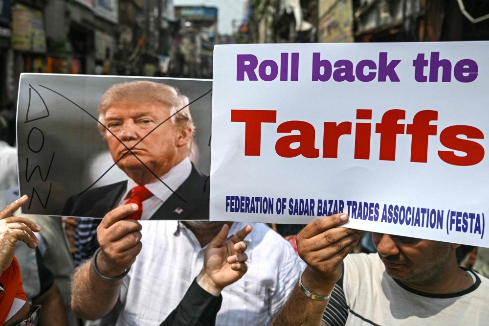 Members of a trades association hold a poster of US President Donald Trump during a protest against the recent tariff hikes imposed by the US on India in New Delhi on August 30, 2025. — AFP pic