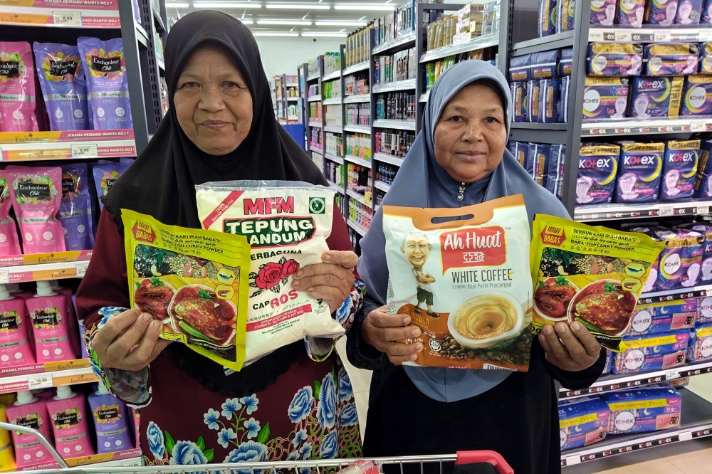 Azizah Mat Desa (left) shows the essential items she bought using the RM100 Sumbangan Asas Rahmah (Sara) aid at a supermarket in Pendang August 31, 2025. — Bernama pic