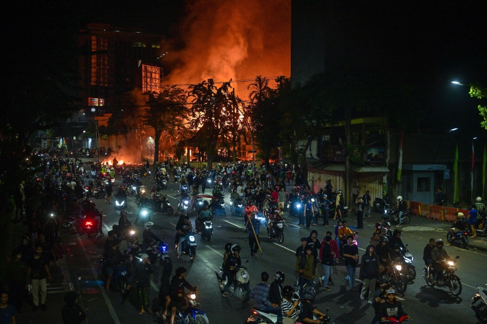 Protesters rides motorcycles in front of a police headquarters that was burned and looted during demonstrations in Surabaya August 31, 2025. — AFP pic