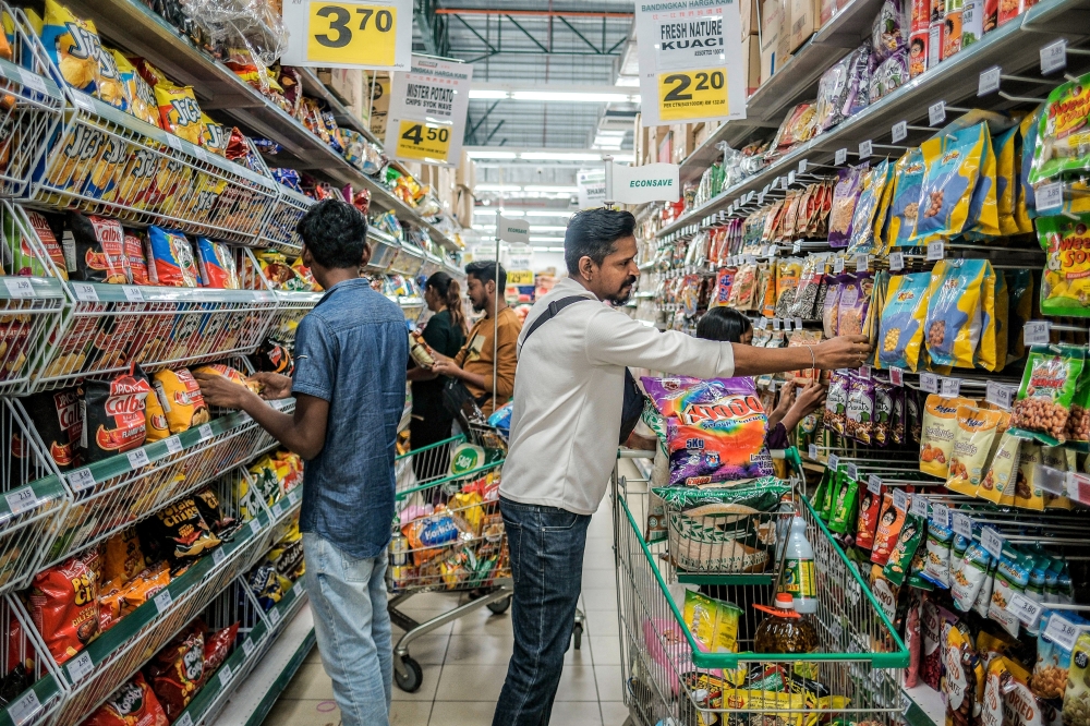 P. Segar (right) uses the RM100 Sumbangan Asas Rahmah (SARA) aid to buy daily essentials on the second day of its rollout at Econsave Kangkar Pulai. The one-off aid, channelled via MyKad, benefits 22 million Malaysians with a RM2 billion allocation. — Bernama pic