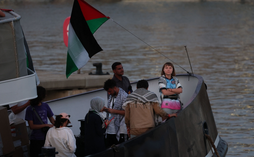 Swedish climate activist Greta Thunberg (right) is seen on board of a vessel of a civilian flotilla, carrying pro-Palestinian activists, and humanitarian aid and aiming to break the Israeli blockade of the Gaza Strip, remains moored at Barcelona port on September 1, 2025, after being forced to return due to bad weather. — AFP pic