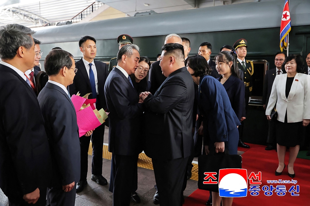 North Korea's leader Kim Jong Un (centre R) and his daughter Kim Ju Ae (4th R) being greeted by China's Foreign Minister Wang Yi (centre L) upon their arrival at the Beijing Railway Station in Beijing yesterday. — AFP pic 