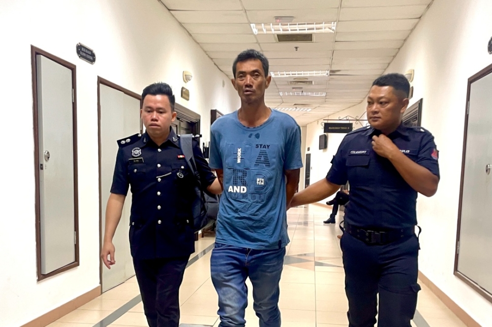 The accused is escorted by police at the court. — The Borneo Post pic