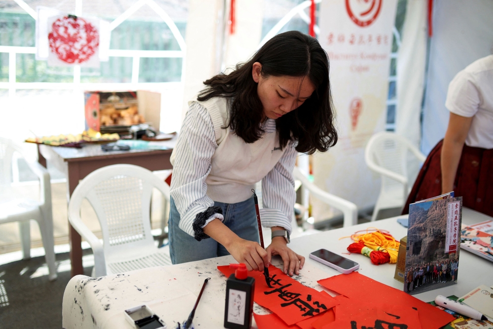 A participant from China presents calligraphy during the Yogurt Festival in the village of Momchilovtsi, Bulgaria, August 30, 2025. — Reuters pic
