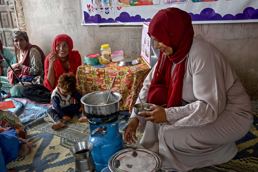 This photograph taken on July 29, 2025 shows a female health worker (right) teaching mothers how to prepare nutritious meals for their children during a Unicef nutrition programme at Fateh Muhammad Soomro village in the Sujawal district of Sindh province. — AFP  pic 