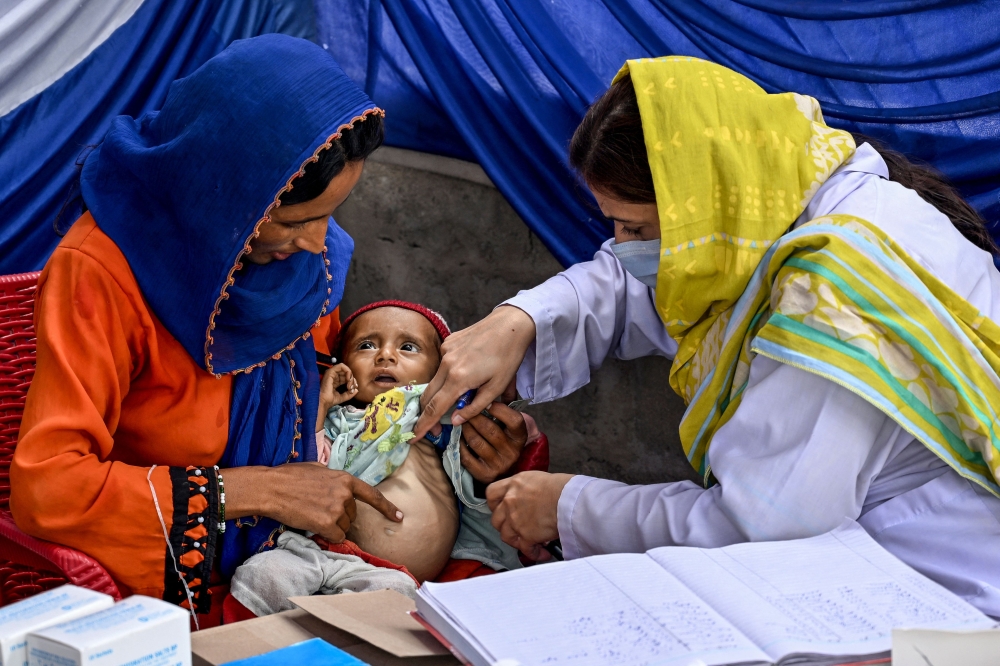 This photograph taken on July 29, 2025 shows a female doctor (right) examining a child during a Unicef nutrition programme at Fateh Muhammad Soomro village in the Sujawal district of Sindh province. — AFP pic 