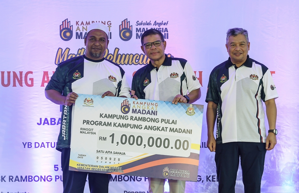 Home Minister Datuk Seri Saifuddin Nasution Ismail presents the Madani Adopted Village contribution to Kampung Rambong Pulai representative Mohd Shukri Shahabudin at the launch of the Madani Adopted Village and Adopted School programme by the Malaysian Immigration Department at Sekolah Kebangsaan Rambong Pulai in Kupang September 5, 2025. — Bernama pic