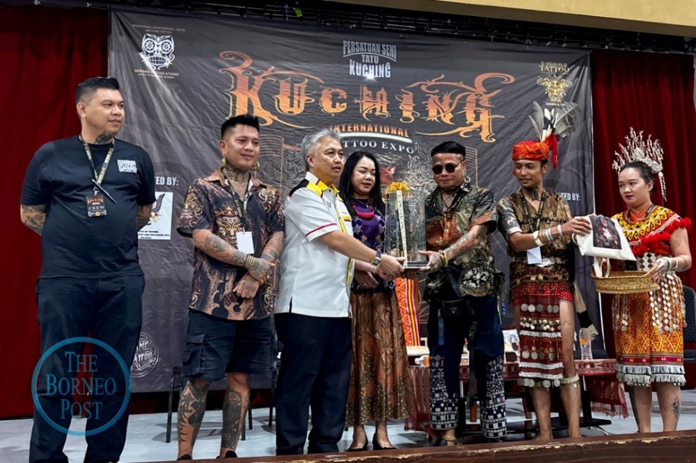 Boi (3rd right) presents a memento to Snowdan, accompanied by (from left) Maximillian, Nicholas and other guests during the expo in Kuching. — The Borneo Post pic