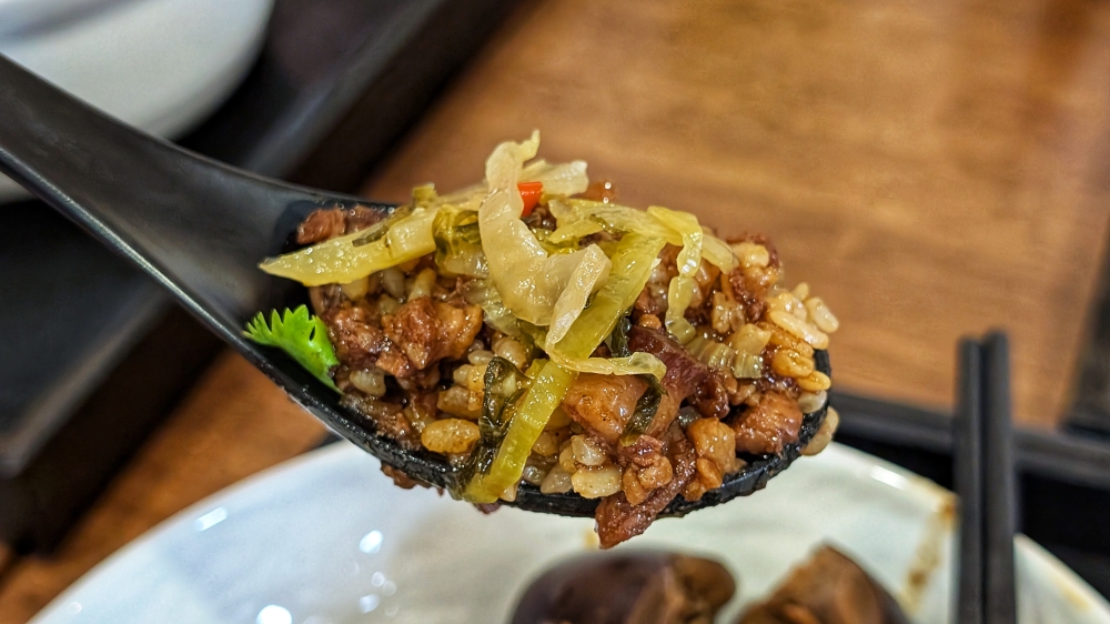A perfect bite of braised pork, rice and pickled mustard greens. — Picture by Ethan Lau