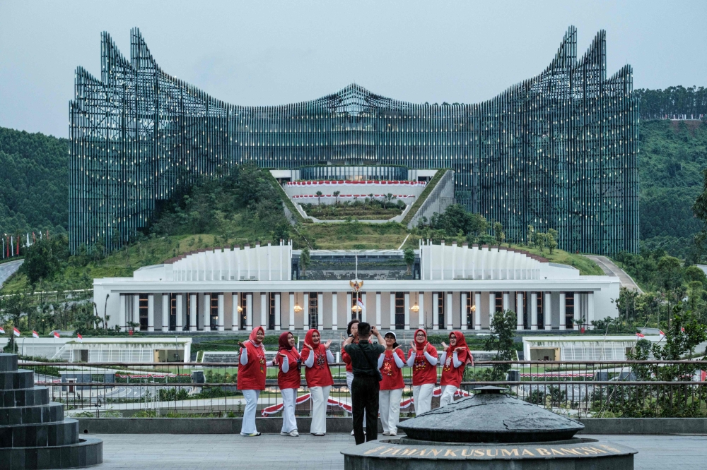This picture taken on August 14, 2025 shows women posing for pictures with the Presidential Palace at Kusuma Bangsa Park in Ibu Kota Nusantara (IKN). — AFP pic