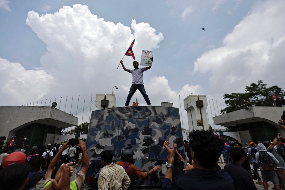 A demonstrator waves a flag as he stands atop a vehicle near the entrance of the Parliament during a protest against corruption and government’s decision to block several social media platforms, in Kathmandu, Nepal September 8, 2025. — Reuters pic
