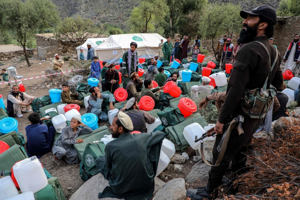 A Taliban security personnel stands guard as earthquake survivors receive aid from the Aga Khan Development Network in the Dewa Gul Valley, Sawkay district, Kunar province, September 5, 2025. More than 2,200 people were killed when a magnitude 6.0 earthquake struck eastern Afghanistan on August 31, the deadliest to hit the country in decades. — AFP pic