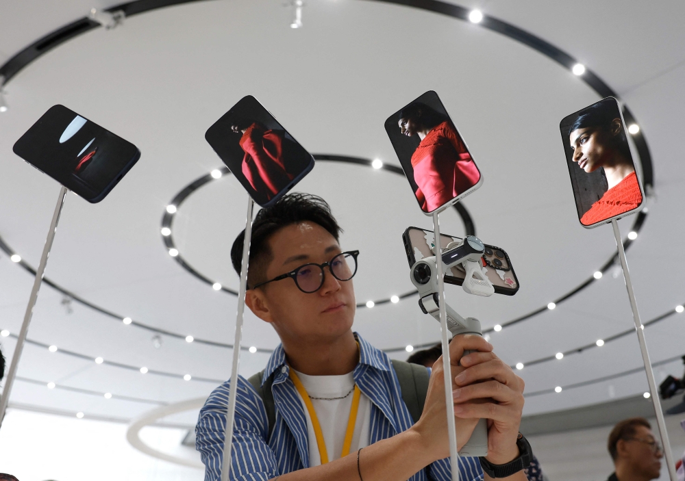 An attendee takes a video of a display of new Apple iPhone 17 Pros during an Apple special event at Apple headquarters in Cupertino, California, September 9, 2025. — AFP pic