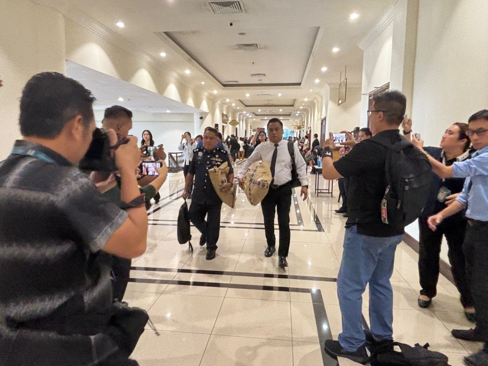 Maidon Bernadus (left) carries part of the mannequin used in the reconstruction of the scene where Zara Qairina Mahathir allegedly fell from the third storey of her school dormitory. — Picture by Julia Chan