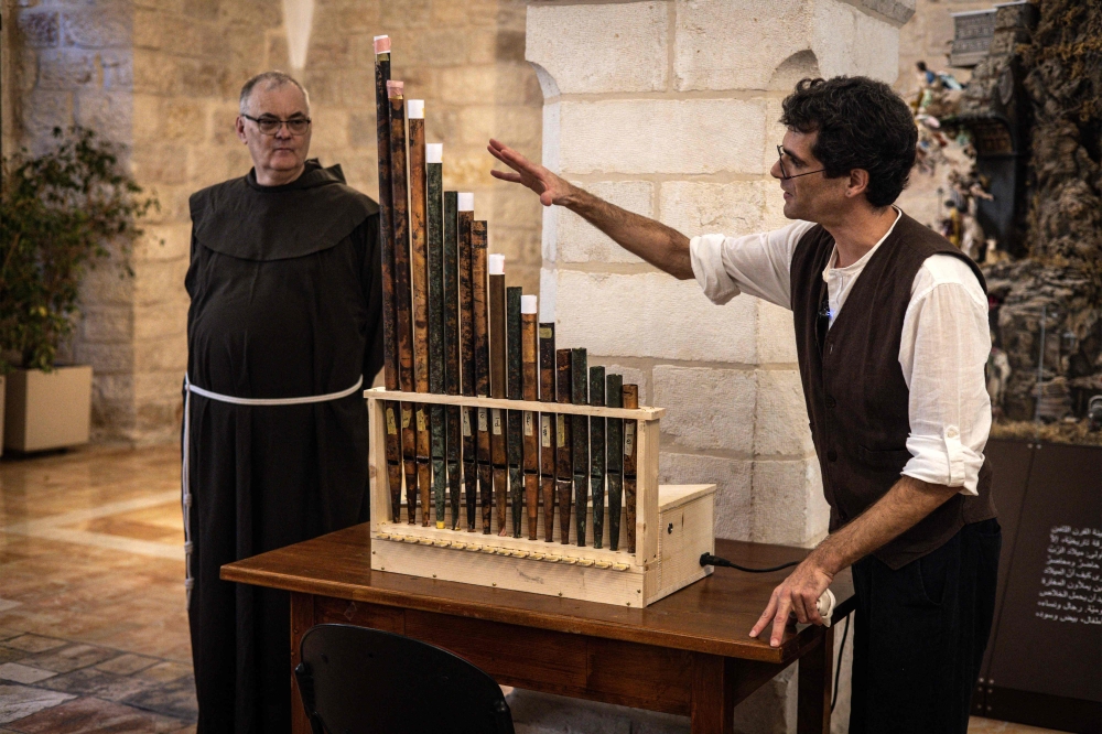 Medieval musicologist David Catalunya (L) gives a briefing about the history of a functioning replica containing original pipes from the oldest organ in Christendom, during the instrument's unveiling and playing at the Saint Saviour Monastery in the old city of Jerusalem on September 9, 2025. — AFP pic