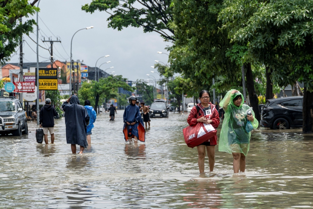 People carrying their belongings wade through a flooded street following overnight heavy rains in Legian, Badung, Bali, Indonesia September 10, 2025. — Reuters pic 