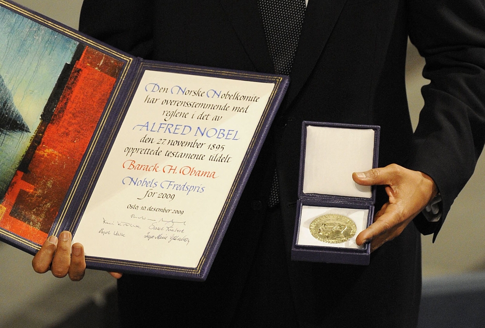 Nobel Peace Prize laureate and US President Barack Obama poses on the podium with his diploma and gold medal during the Nobel ceremony at City Hall in Oslo on December 10, 2009. — AFP pic