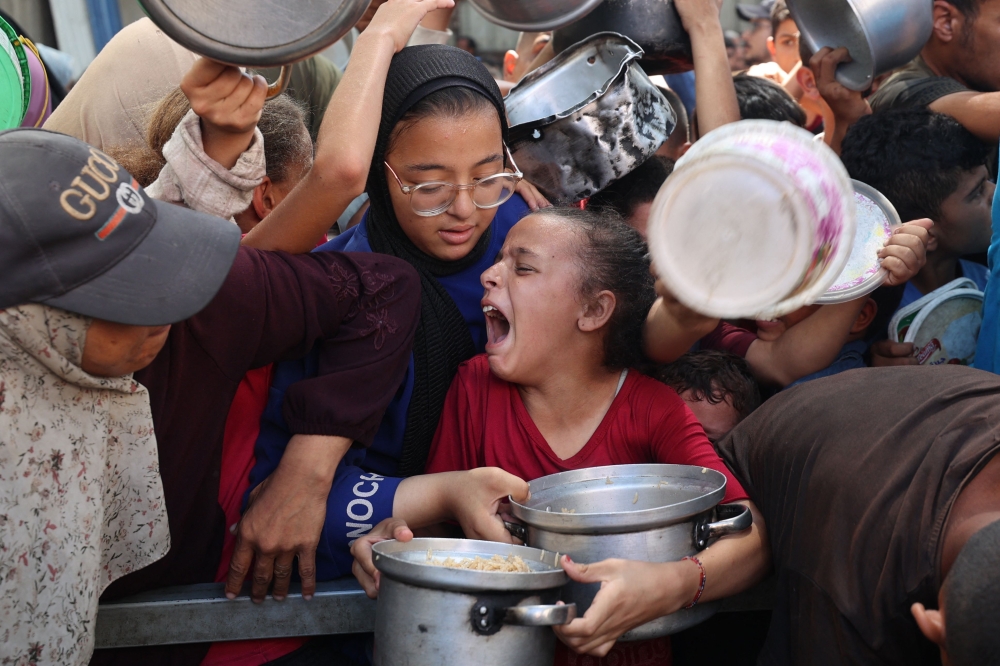 Palestinians queue to receive a hot meal from a charity kitchen in the Nuseirat refugee camp in the Israel-besieged Gaza Strip on September 11, 2025, amid a UN-declared famine after nearly two years of war. — AFP pic
