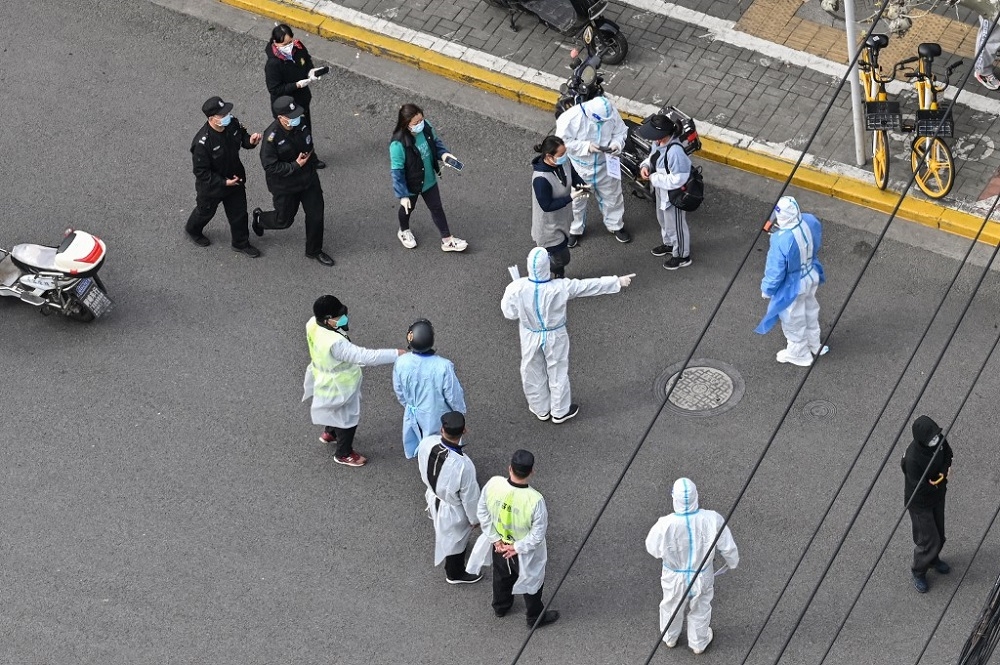 A health worker (centre) wearing personal protective gear gestures to residents on a street during the second stage of a Covid-19 lockdown in Jing’an district in Shanghai in this file picture dated April 1, 2022. — AFP pic 