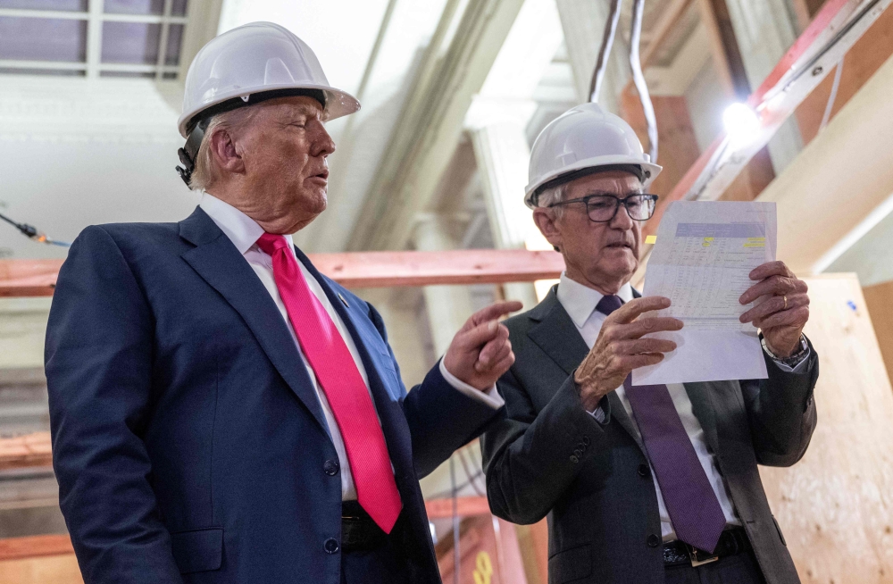 US President Donald Trump points to a cost sheet as he speaks with Federal Reserve Chair Jerome Powell during a visit to the Fed in Washington July 24, 2025. — AFP pic