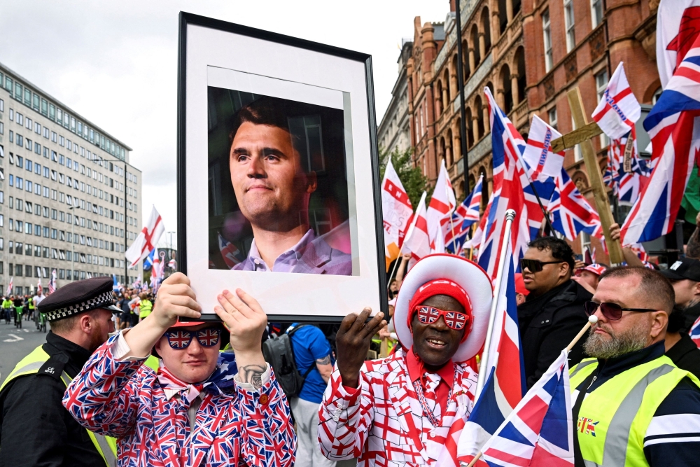 Protesters hold a picture of US conservative activist Charlie Kirk, who was fatally shot while speaking at an event at Utah Valley University, on the day of an anti-immigration rally organised by British anti-immigration activist Stephen Yaxley-Lennon, also known as Tommy Robinson, in London September 13, 2025. — Reuters pic