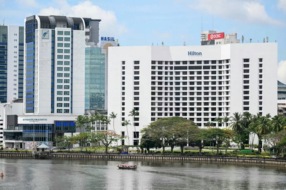 A water taxi is pictured on the Sarawak river in front of a Hilton hotel and commercial buildings in Kuching, capital of the Malaysian state of Sarawak on the island of Borneo, on June 18, 2025. — AFP pic 