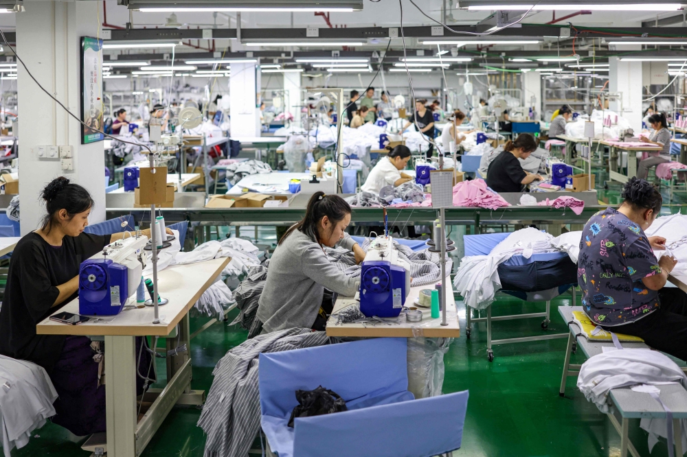 Employees sew clothes for export at a clothing factory in Tongren, in southwestern China's Guizhou province May 15, 2025. — AFP pic