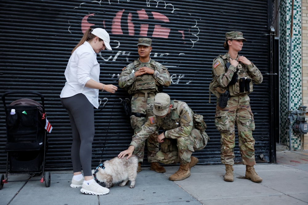 A member of the Ohio National Guard pets a cat while others stand weeks after US President Donald Trump ordered an increased presence of federal law enforcement to assist in crime prevention, in Washington, D.C. September 12, 2025. — Reuters pic 