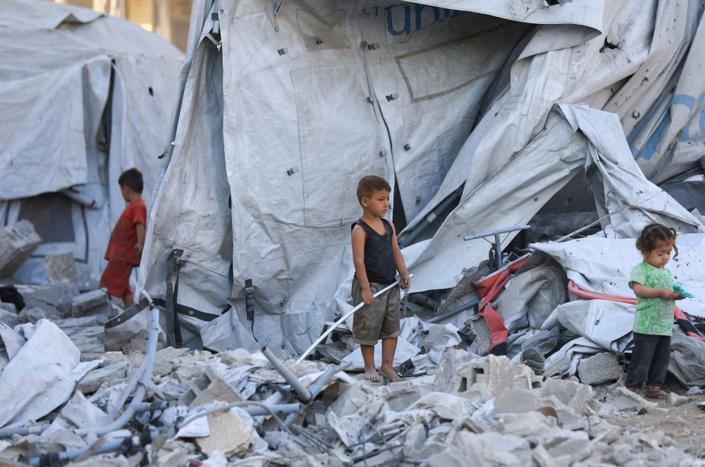Palestinian children stand at a tent camp sheltering displaced people after it was damaged in a nearby Israeli strike that destroyed a residential building, in Gaza City, September 9, 2025. — Reuters pic