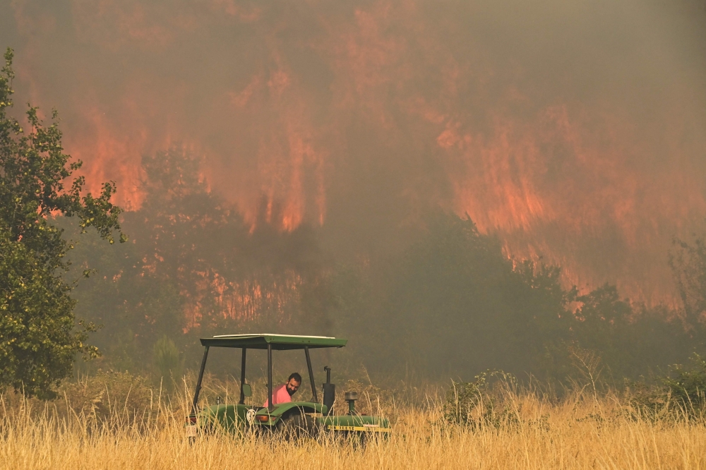 A resident tries to battle a wildfire in the village of Santa Baia de Montes in the province of Ourense, north-western Spain, on August 14, 2025. — AFP pic 