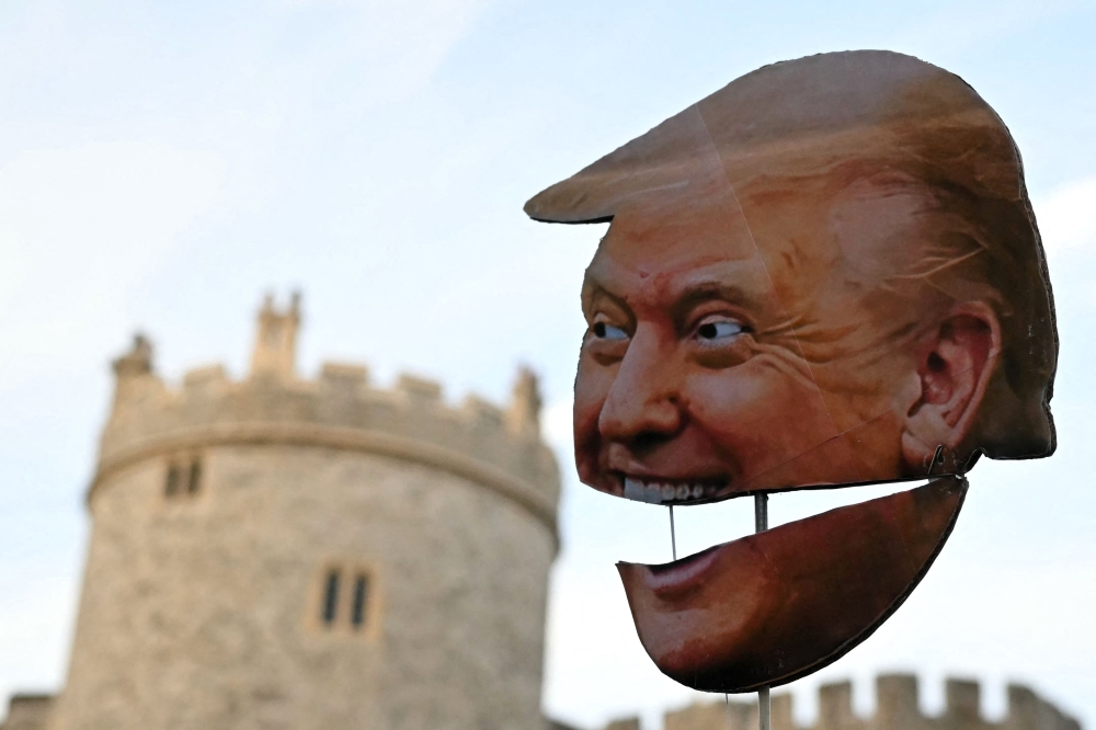 A demonstrator holds a placard of the US President's face during a protest against the forthcoming State Visit of US President Donald Trump, outside Windsor Castle in Windsor on September 16, 2025. — AFP pic 