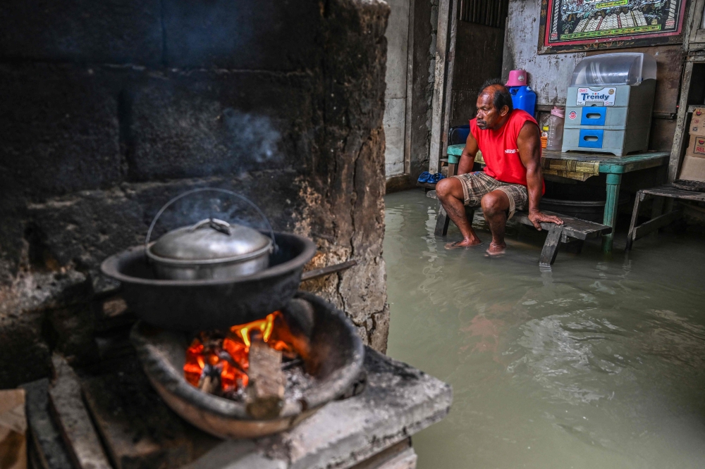 A resident sits on a bench outside his flooded home in Calumpit, Bulacan, September 17, 2025. — AFP pic