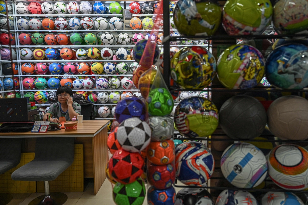 A vendor waits for customers at a sporting goods store selling soccer balls at the Yiwu International Trade Market. — AFP pic