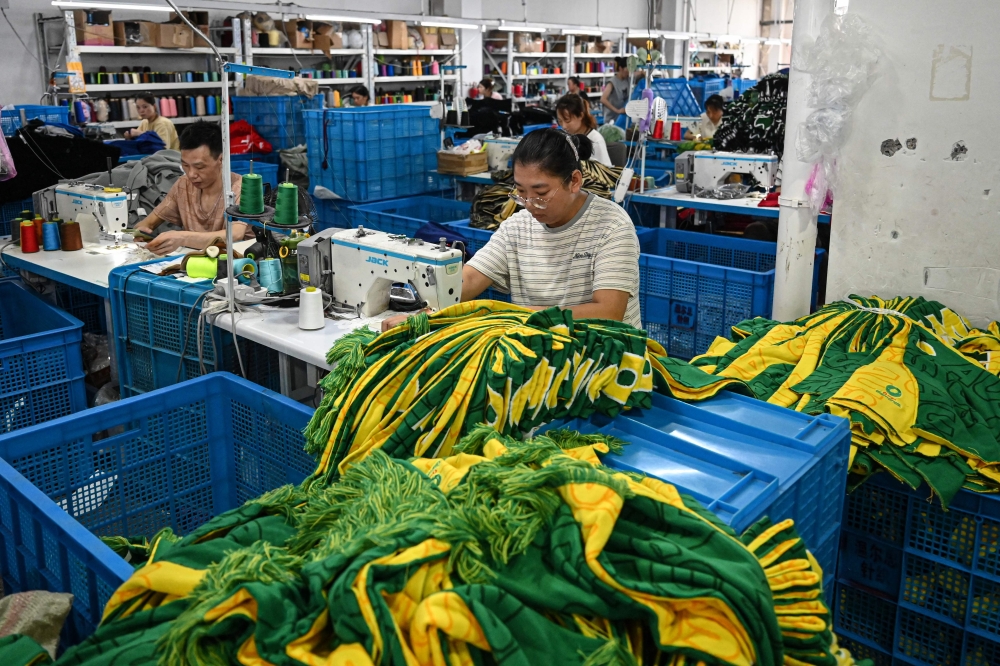 Employees sew scarves at a factory that produces hats and scarves in Yiwu. — AFP pic