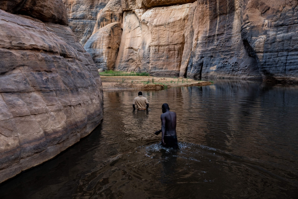 Celestin Gabi (R), PhD student in archaeology, and Mahamat Ahmat Oumar (L), archaeological coordinator for the cultural heritage department of the Ennedi Natural and Cultural Reserve for African Parks, walk through the Guelta d'Archei, in Ennedi Ouest province, on July 13, 2025. — AFP pic