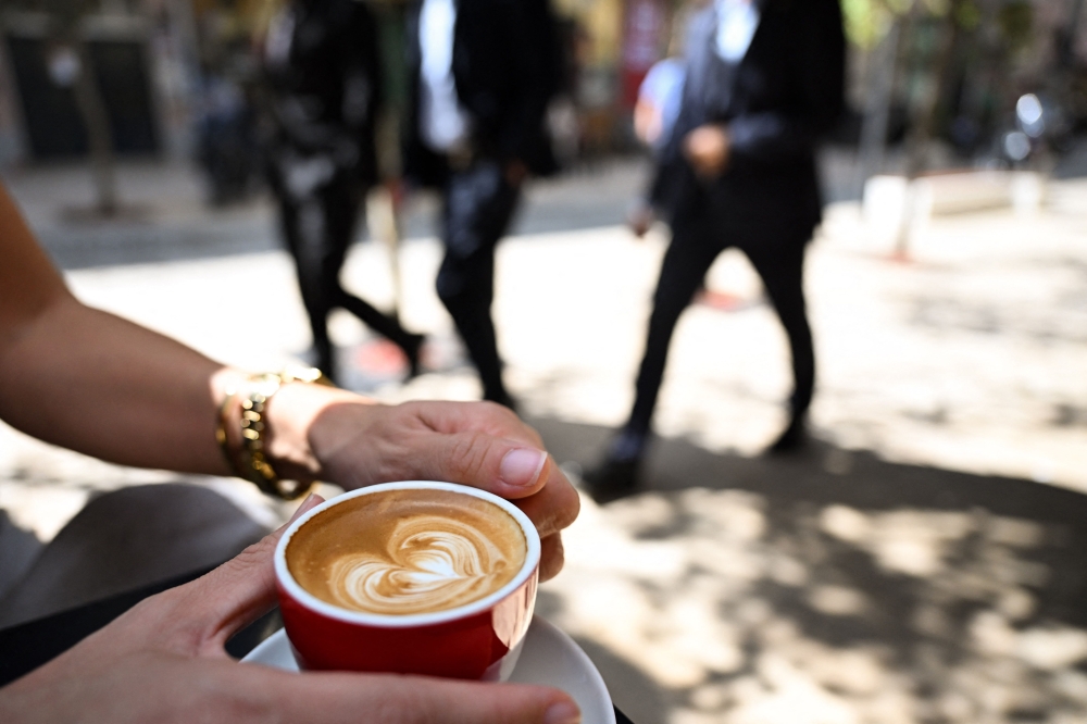 A customer holding macchiato coffee at a terrace table of a coffee shop in Pristina. — AFP pic