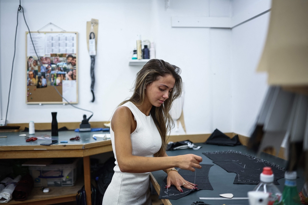 Apprentice tailor Wendy sows fabric inside Henry Poole & Co on Savile Row in London on August 12, 2025. — AFP pic 